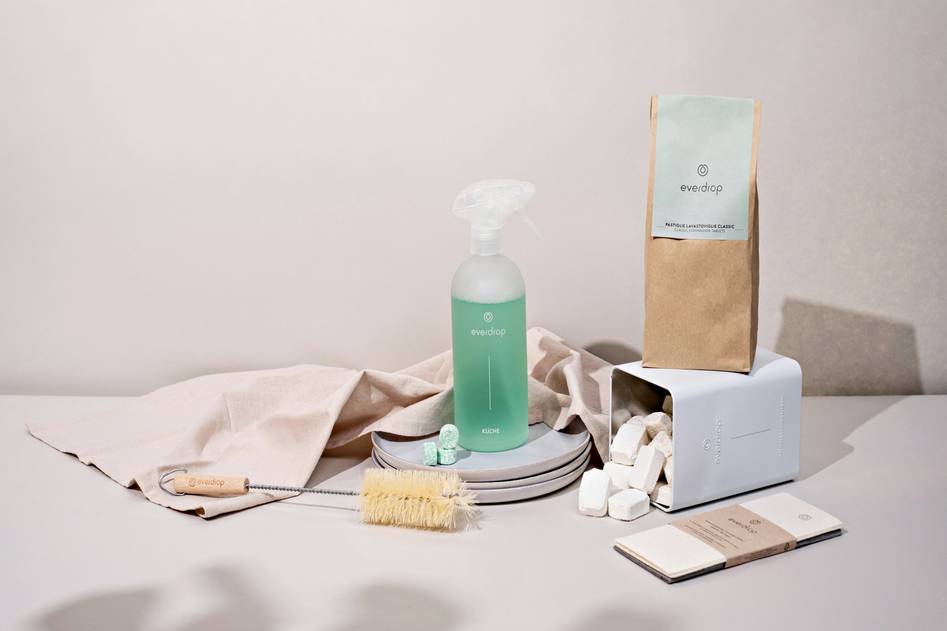 Eco-friendly biodegradable dish soap bottle on wooden counter with fresh herbs