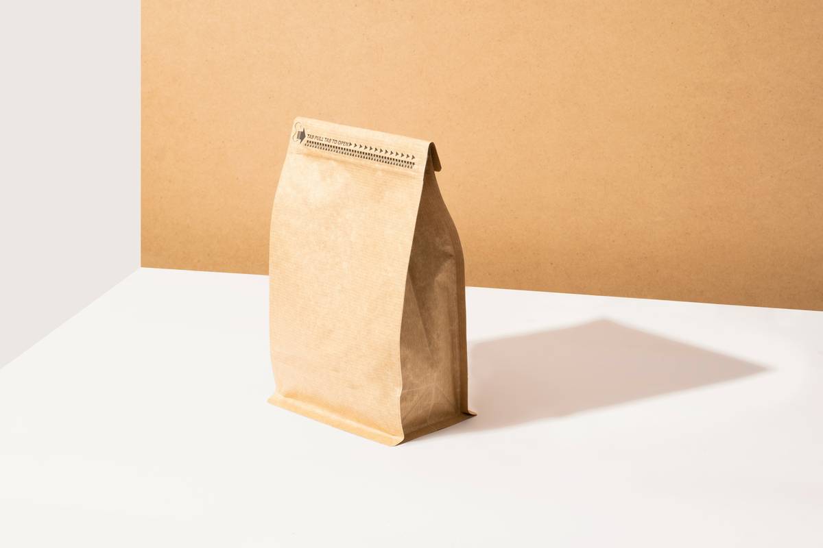 Stack of biodegradable paper products for food service including cups, containers, and napkins on a rustic wooden counter