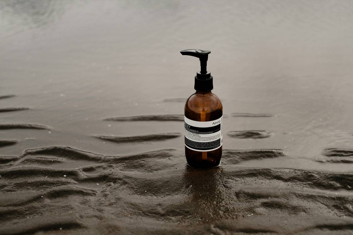 Hands washing dishes with bio friendly dish soap in a kitchen sink surrounded by reusable bottles and natural sponges